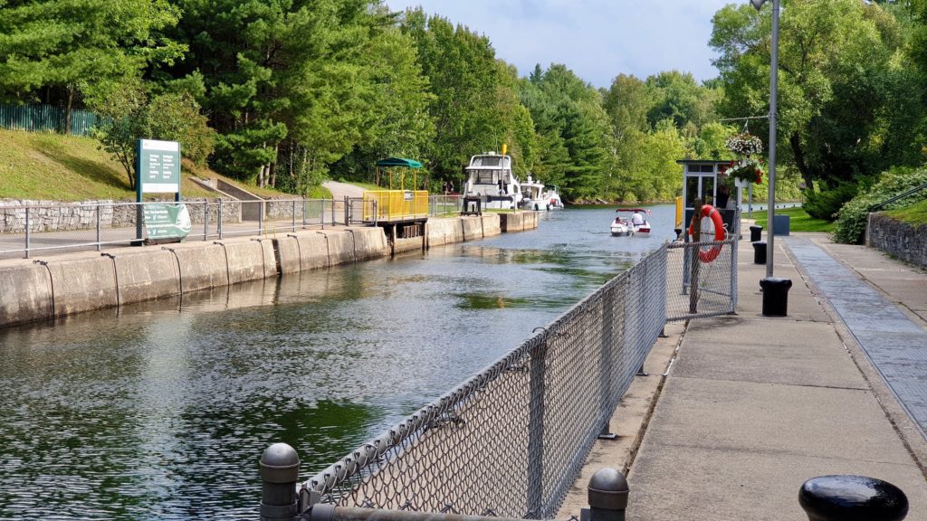 A small boat heads out of the Couchiching Lock and down the Trent-Severn Waterway