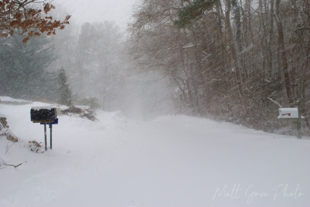 Wind-blown snow swirls on a desolate road during a blizzard