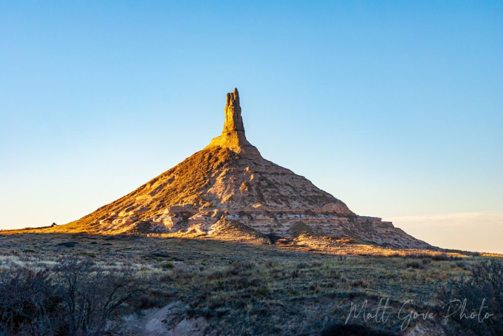 The setting sun bathes Chimney Rock in a warm light